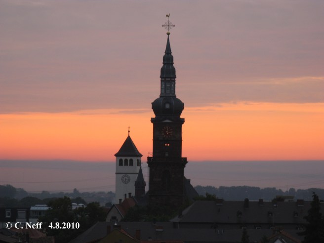 morgentlicher Blick auf St. Martin Grünstadt (ev.) - es ist 6.17 aber die Kirchturmuhr zeigt seit dem 6.6.2010 immer12 Uhr 17 an ! Im Hintergrund sieht man St. Peter (kath) mit der richtigen Uhrzeit, © C.Neff 4.8.2010
